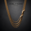 Ceroundmi London gold multi-strand rope chain necklace with pavé crystal knot and tassel ends, displayed on dark background