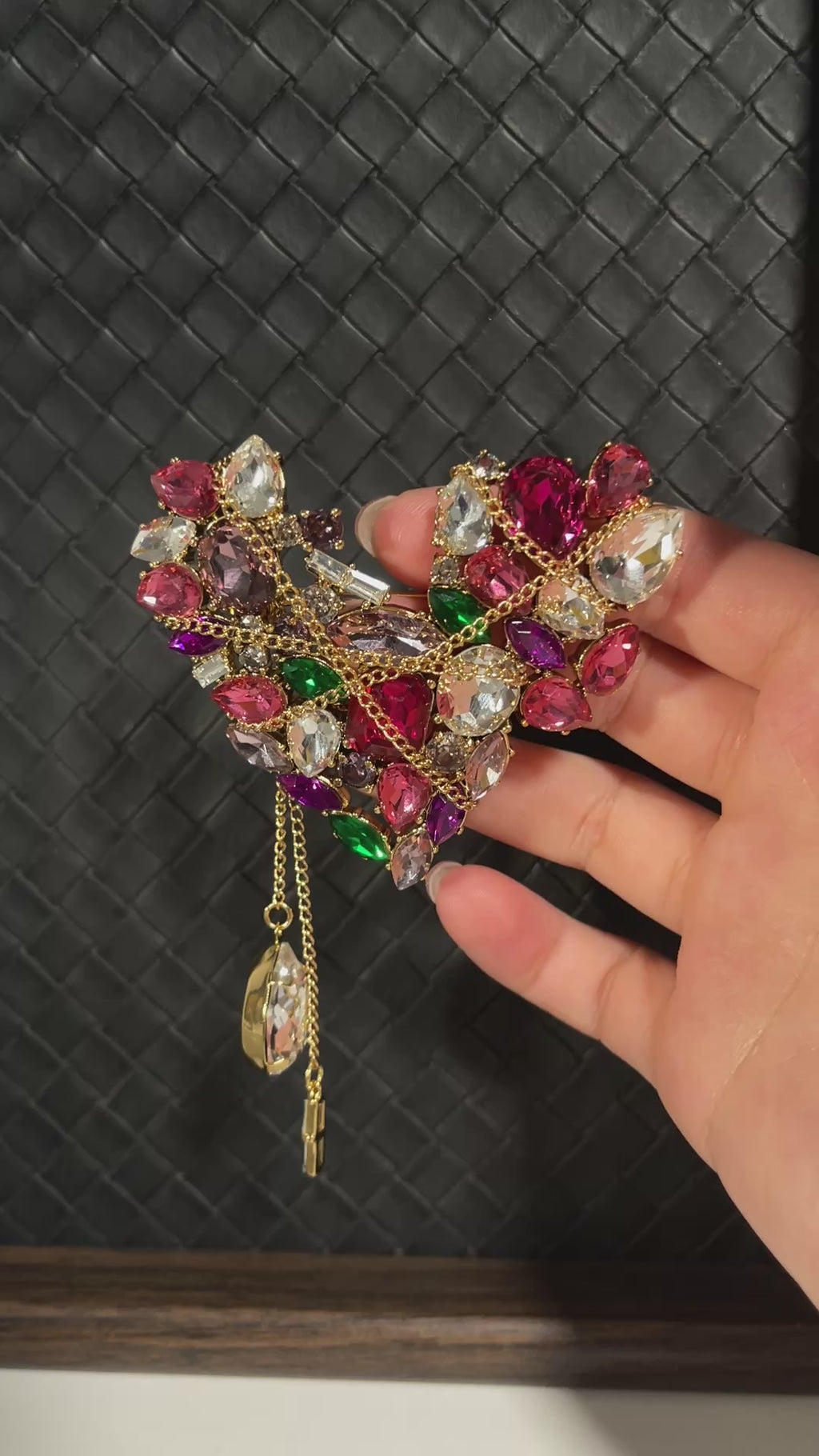 Short video showing a vintage-inspired heart-shaped crystal brooch with colourful stones, gold-tone chain details and dangling crystal tassels catching the light.