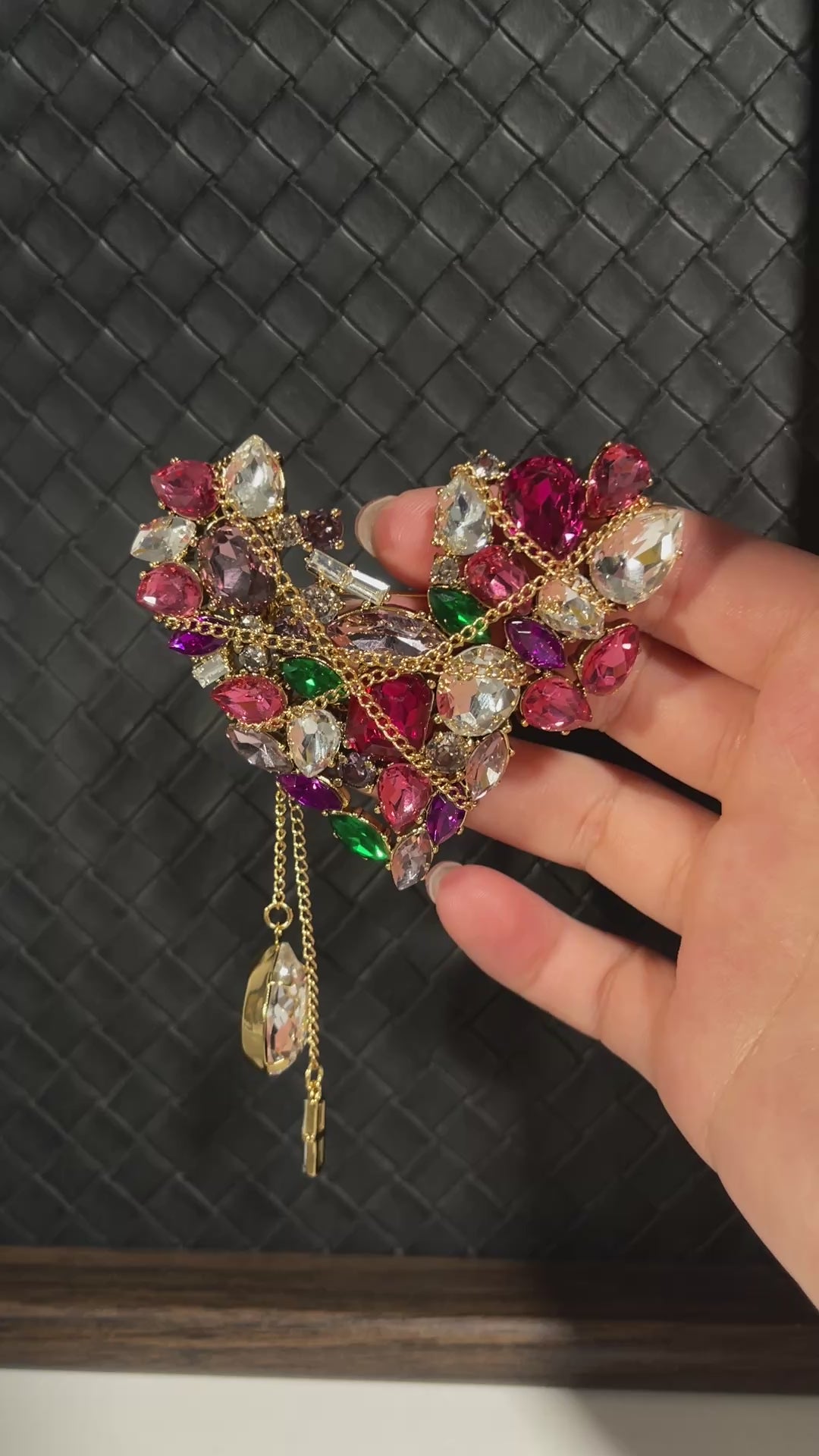 Short video showing a vintage-inspired heart-shaped crystal brooch with colourful stones, gold-tone chain details and dangling crystal tassels catching the light.